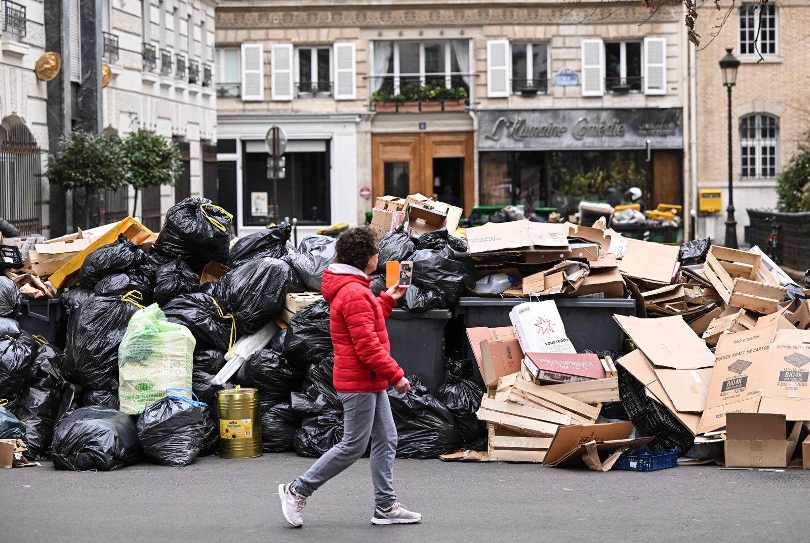Pedestre passa por um monte de lixo acumulado em uma rua de Paris, durante greve contra a reforma previdenciária proposta pelo governo francês — Foto: Stefano RELLANDINI / AFP