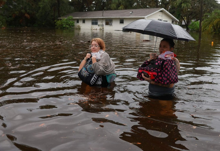 Makatla Ritchter (e) e sua mãe, Keiphra Line, atravessam as águas da enchente depois de terem que deixar sua casa quando as águas da enchente do furacão Idalia