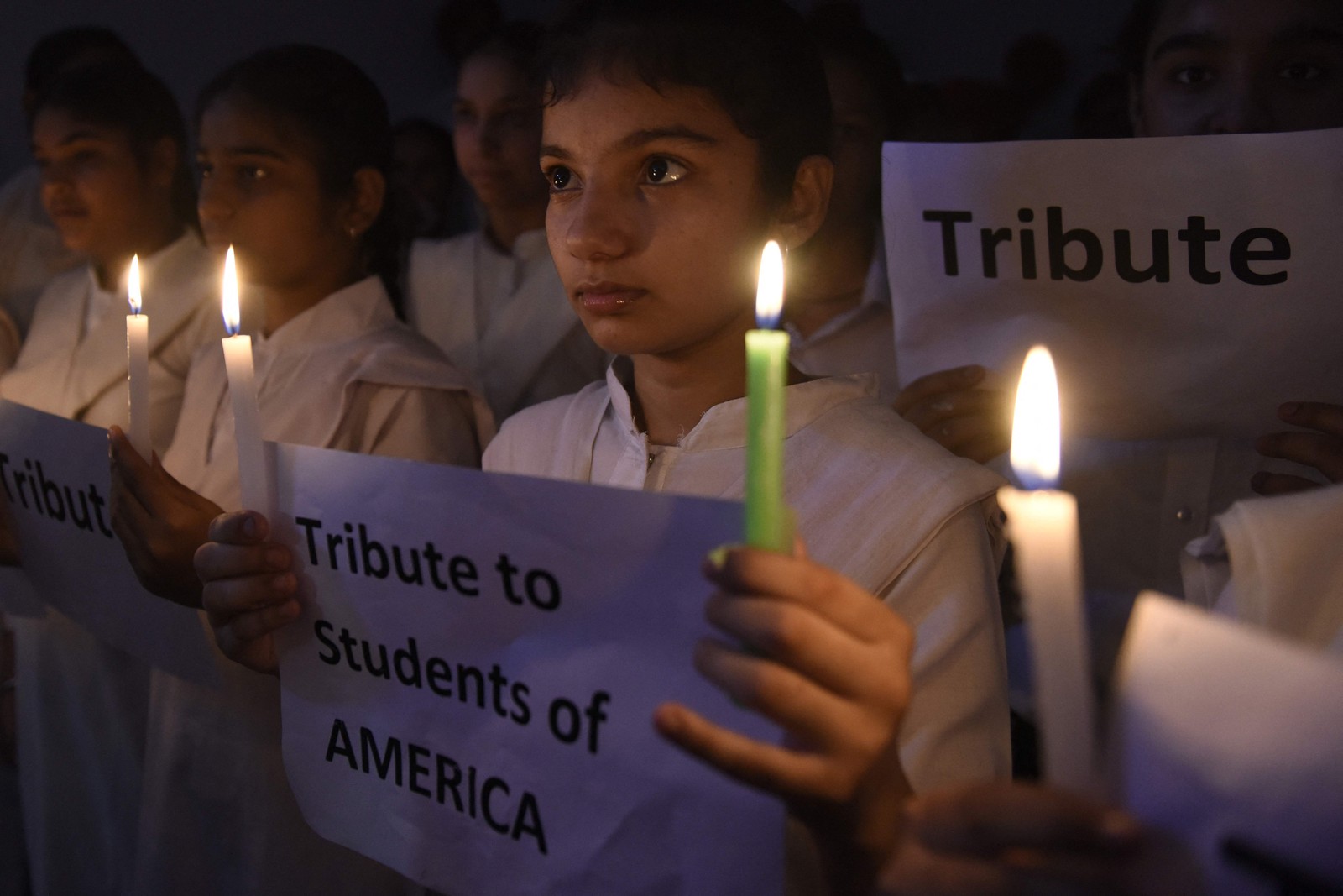Estudantes seguram velas e cartazes em homenagem às vítimas do ataque à escola na comunidade latina no Texas — Foto: NARINDER NANU / AFP