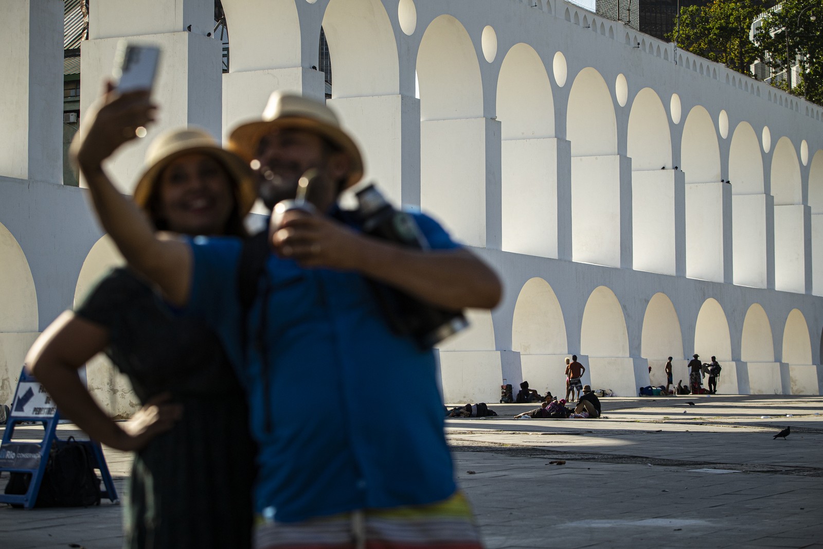 Turistas fazem selfie nos Arcos da Lapa, onde pessoas em situação de rua se abrigam — Foto: Hermes de Paula / Agência O Globo