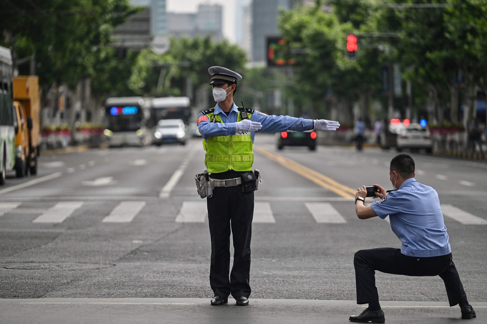 Policial fotografa colega enquanto controlava o tráfego no distrito de Jing'an, em Xangai, após o fim do lockdown que manteve a cidade dois meses com restrições pesadas — Foto: HECTOR RETAMAL / AFP