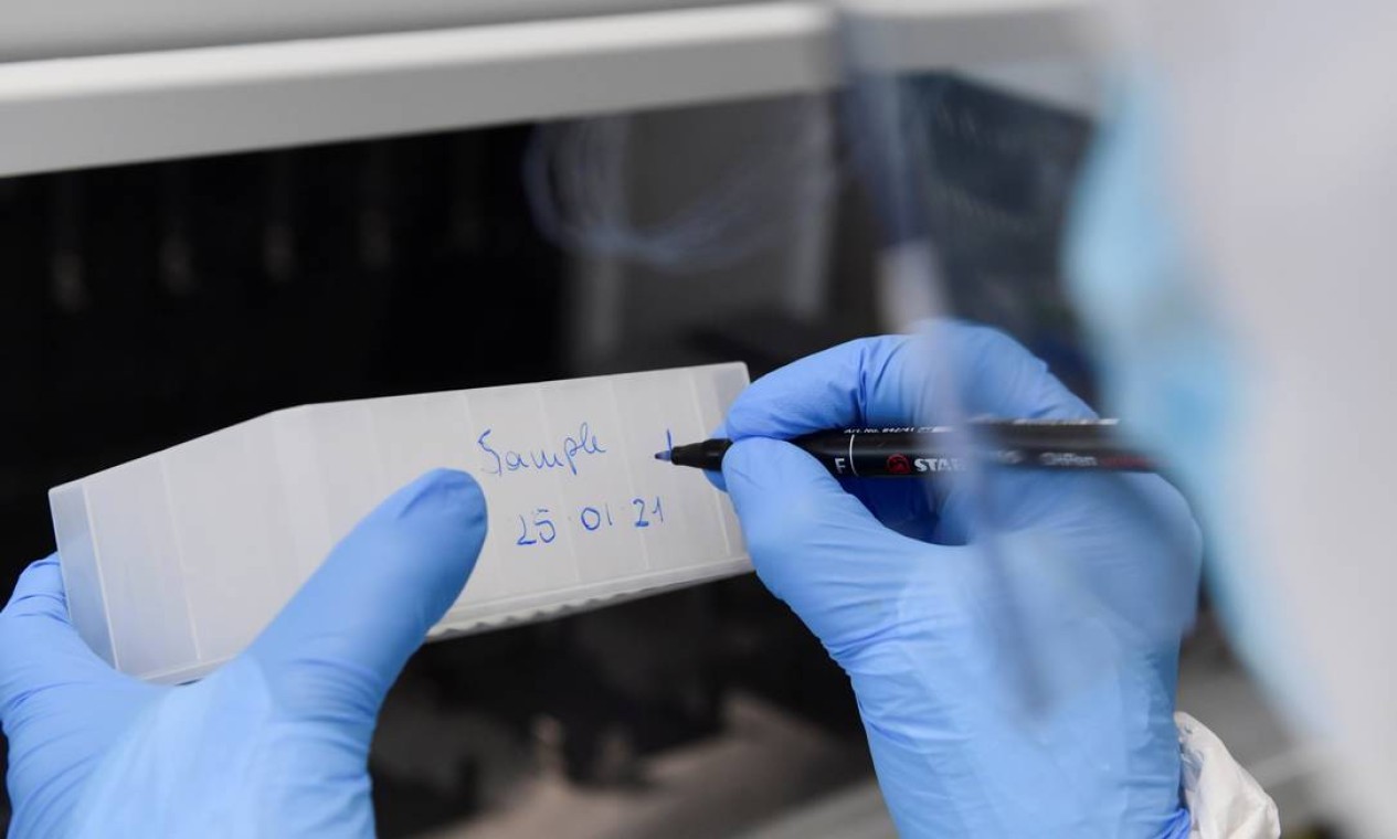 Trabalhador médico escreve em um contêiner em um laboratório dentro do centro de testes central de Milão (CDI), onde milhares de cotonetes da COVID-19 são testados a cada dia, em Milão, Itália — Foto: JENNIFER LORENZINI / REUTERS