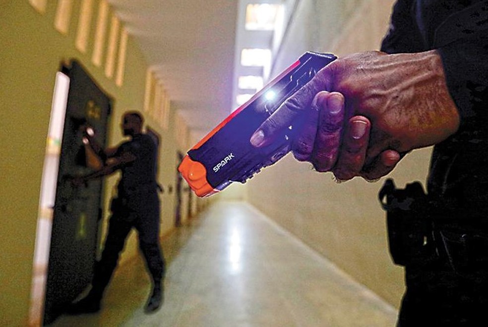 Penitenciária de Brasília: enquanto um agente se aproxima da cela, o outro faz vigília com arma de choque — Foto: Agência O Globo/Cristiano Mariz