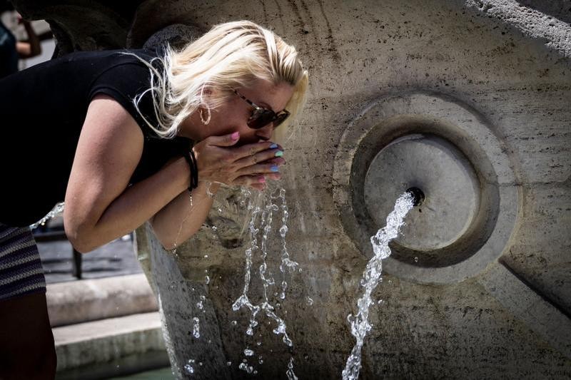 Mulher se refresca na Fontana della Barcaccia, em Roma, na Itália, em meio à onda de calor que atinge a Europa. — Foto: Tiziana FABI / AFP