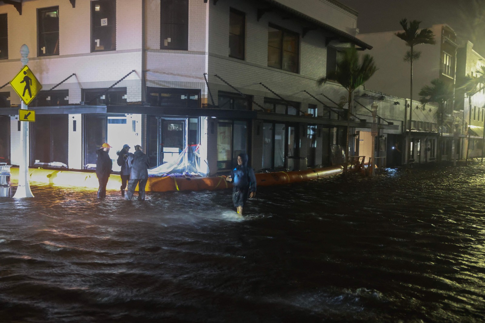 Equipes de imprensa trabalham em ruas inundadas depois que o furacão Milton atingiu a área em Fort Myers — Foto: Joe Raedle/Getty Images/AFP