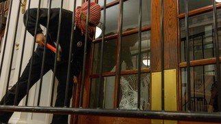 Um manifestante quebra as janelas da porta da frente do prédio para prender uma corrente em torno dele para impedir a entrada das autoridades na terça-feira, 30 de abril de 2024, na cidade de Nova York. — Foto: Alex Kent/Getty Images/AFP