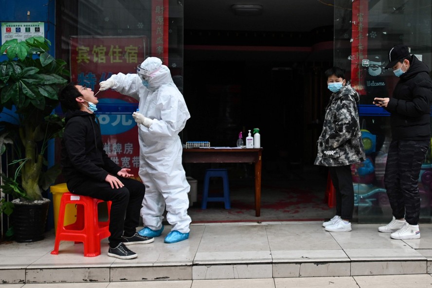 Profissional de saúde testa morador de Wuhan, na China, durante pandemia de Covid-19