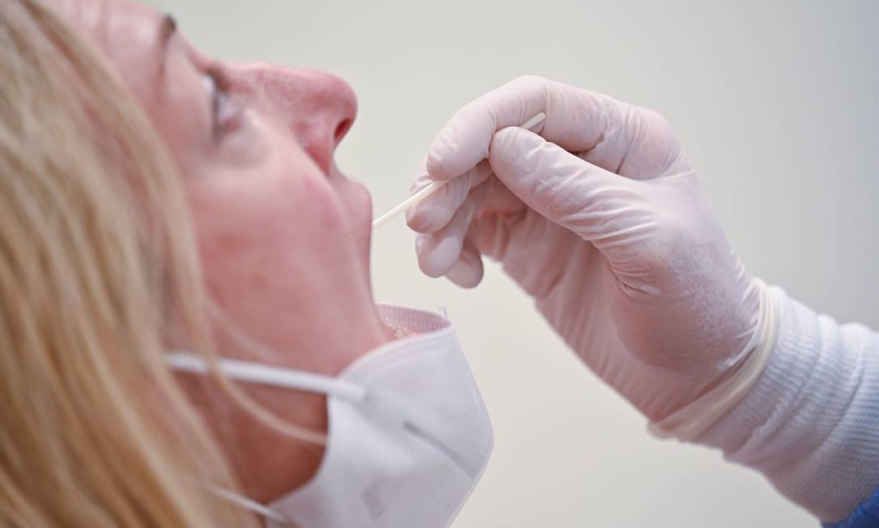 Funcionário coleta um cotonete antes de processar a amostra para testar Covid-19, no laboratório do Biogroup Laboratory, no oeste de Londres — Foto: JUSTIN TALLIS / AFP