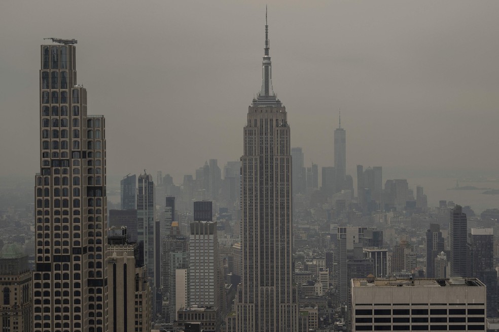 NOVA YORK, NOVA YORK – 16 de julho: A fumaça dos incêndios florestais no Canadá encobre o horizonte de Manhattan, incluindo o Empire State Building, vista do mirante Top of the Rock, em 16 de julho de 2026, na cidade de Nova York. Grande parte da Costa Leste dos Estados Unidos e do Canadá está sob alerta de saúde devido à qualidade do ar, enquanto a fumaça dos incêndios no Canadá e na região dos Grandes Lagos avança lentamente pela área, formando uma densa névoa em meio ao calor. A região enfrenta mais uma onda de calor, com índices de sensação térmica superiores a 38°C — Foto: David Ramos / GETTY IMAGES NORTH AMERICA / Getty Images via AFP