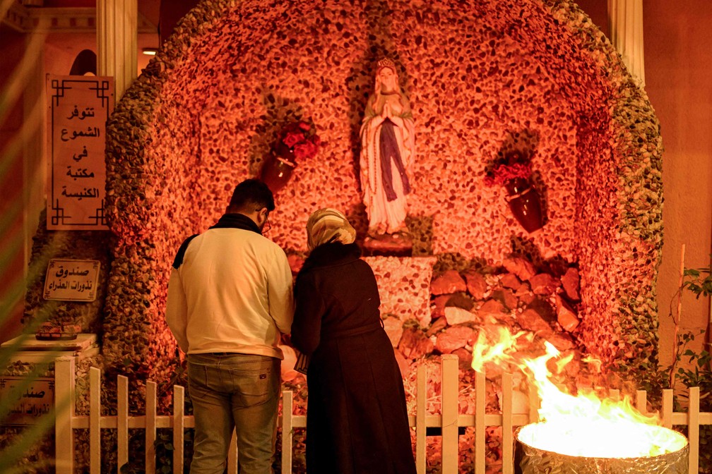 Casal muçulmano no santuário da Virgem Maria durante a cerimônia de véspera de Natal na Catedral Católica Siríaca do Sagrado Coração, na cidade de Basra, no Iraque — Foto: AFP/ Hussein Faleh