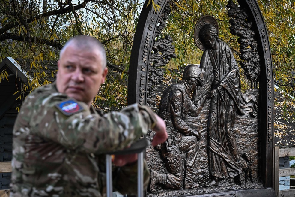 Veterano russo da guerra na Ucrânia diante de monumento religioso aos militares mortos, nos arredores de Moscou — Foto: Olesya KURPYAYEVA / AFP