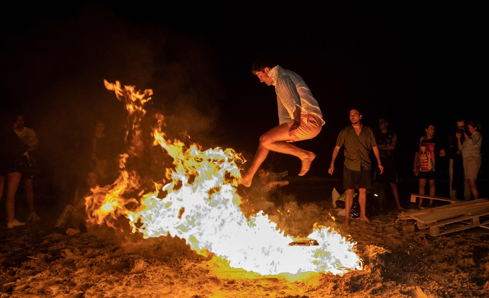 Homem salta uma fogueira durante as celebrações anuais de São João em uma praia em Alicante, Valência, Espanha — Foto: JOSE JORDAN / AFP