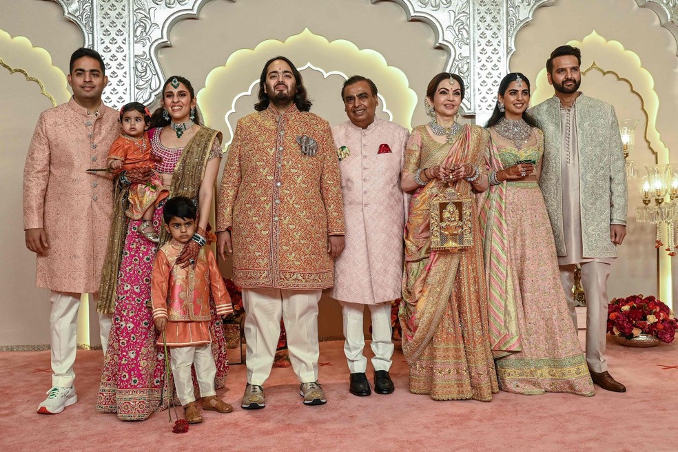 O bilionário indiano Mukesh Ambani (C), com sua esposa Nita Ambani (3D), filha Isha Ambani (2D), filhos Akash Ambani (E) e Anant Ambani (C, esquerda), nora Shloka Mehta (2E) e genro Anand Piramal posam para fotos enquanto chegam para participar da cerimônia de casamento de Anant e Radhika Merchant em Mumbai — Foto: SUJIT JAISWAL / AFP