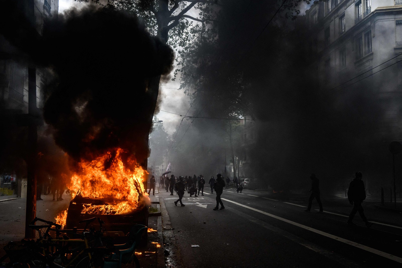 A fumaça enche a rua enquanto as chamas emergem de um carro em chamas incendiado durante uma manifestação em Lyon, no leste da França, em 1º de maio de 2023 — Foto: JEFF PACHOUD / AFP