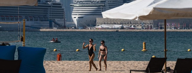 Mulheres caminham na praia de Gas Abou Abboud, em Doha, onde há iates de luxo ancorados — Foto: ANDREJ ISAKOVIC / AFP