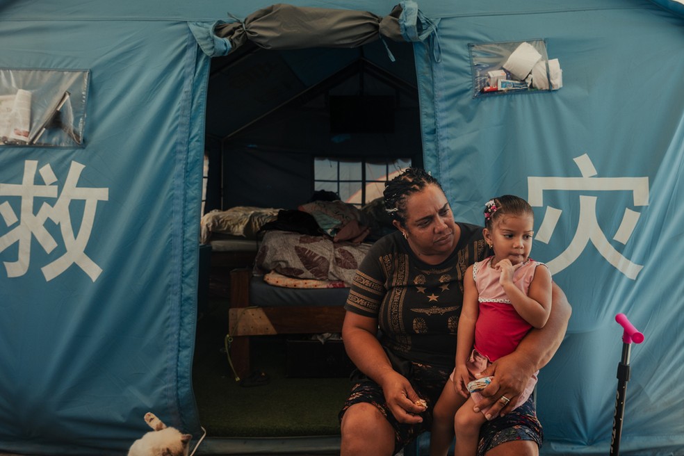Ashley Mayora, de 43 anos, segura sua neta de 3 anos, Greymari Felicia, do lado de fora de sua barraca em um acampamento temporário em Mare Abajo. — Foto: Adriana Loureiro Fernandez/MSF