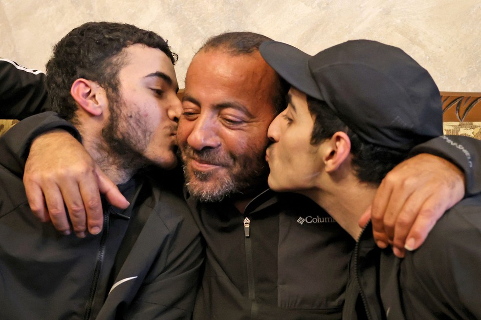 Os irmãos palestinos Qassam (esquerda) e Nasrallah (direita) se reencontram com seu pai Iyad Al-Awar depois de serem libertados de uma prisão israelense — Foto: AFP
