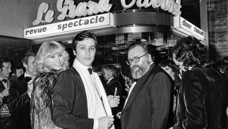 Alain Delon entre a atriz Mireille Darc e o diretor italiano Sergio Leone chegando à reinauguração da badaladíssima boate "Le Grand Cabaret", em 1977 em Nice, França — Foto: AFP