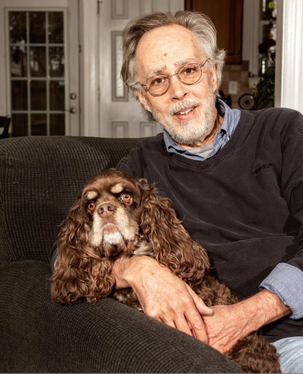 Paul Londraville, que comprou uma máquina de tosar elétrica acoplada a um aspirador de pó para lidar com os pelos de seu cocker spaniel de 4 anos, Oliver, em sua casa em Greensboro, Carolina do Norte — Foto: Jeremy M. Lange/The New York Times