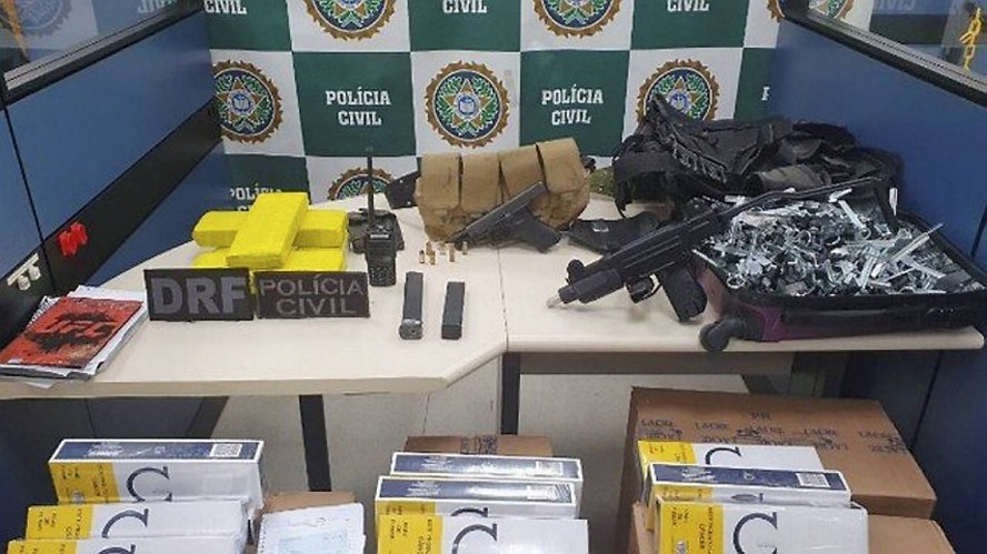 Caixas de cigarro, armas e tabletes de maconha apreendidos pela pol&iacute;cia do Rio