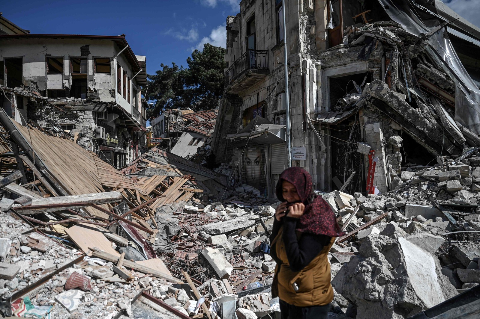 Mulher caminha próximo a escombros de prédios desabados em Hatay, um mês depois do terremoto que matou 46 mil entre Turquia e Síria — Foto: OZAN ​​KOSE/AFP
