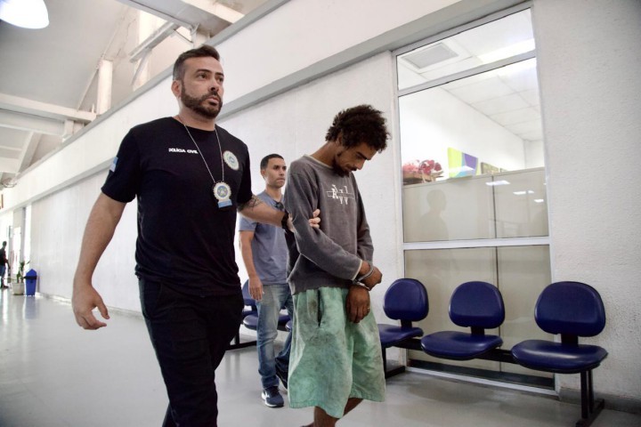 Suspeito chega na Cidade de Polícia. — Foto: Guito Moreto / Agência O Globo