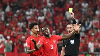 Sam Adekugbe reage ao cartão amarelo do árbitro brasileiro Raphael Claus — Foto: NATALIA KOLESNIKOVA/AFP