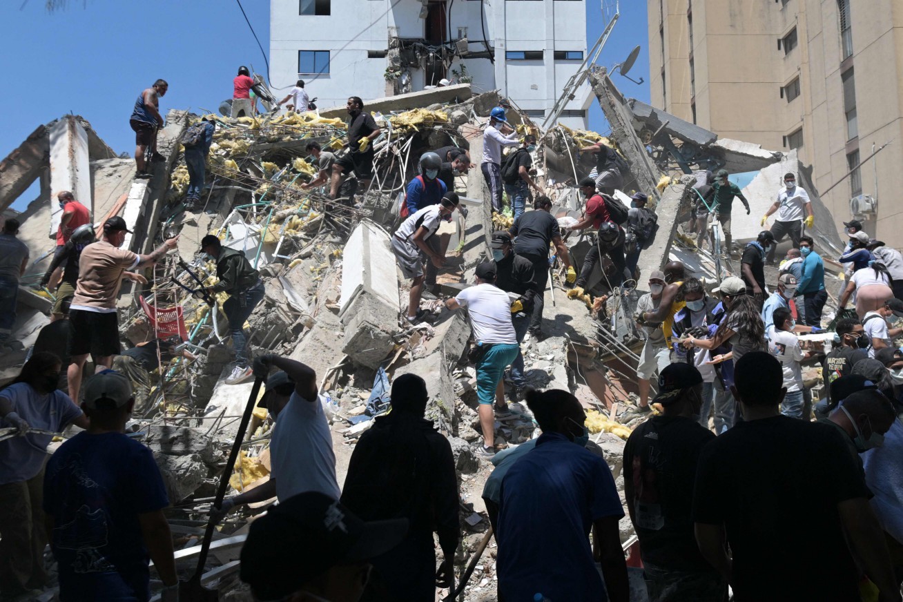 Pessoas procuram por sobreviventes entre os escombros de um edifício desabado após um terremoto em Cali, Colômbia. — Foto: Joaquín SARMIENTO / AFP