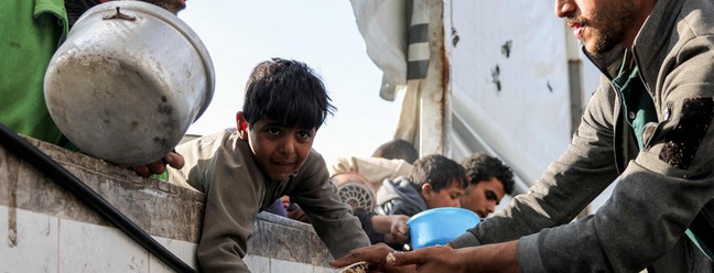 Moradores da Cidade de Gaza levam panelas para receber alimentos doados durante o m&ecirc;s sagrado do Ramad&atilde; &mdash; Foto: BASHAR TALEB / AFP