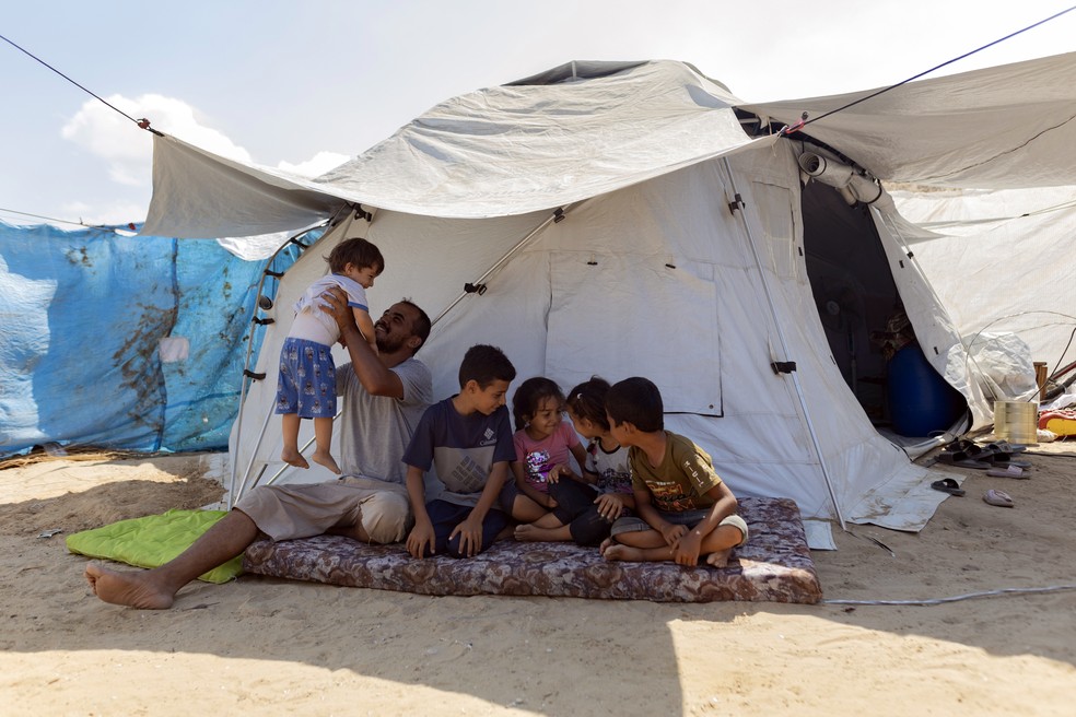 Nidal Eissa e sua família do lado de fora de sua tenda no centro de Gaza — Foto: Saher Alghorra/The New York Times