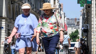 PESSOAS CAMINHAM PELA RUA ENQUANTO umtermômetrroindica depatura de36ºC Durante de Calor