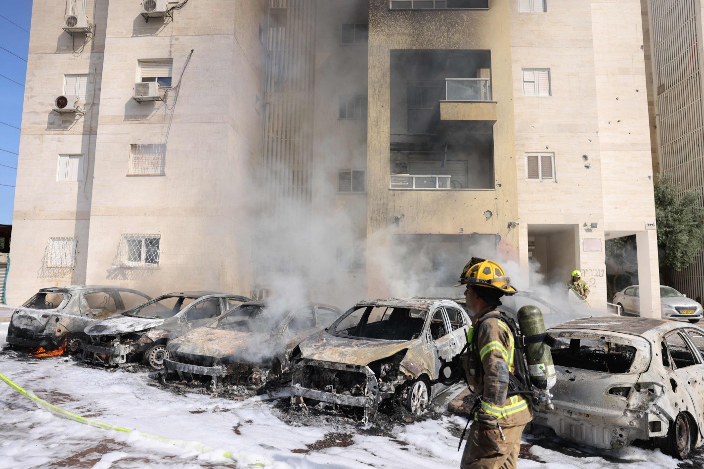 Equipes do Corpo de Bombeiros israelense apagam o incêndio em um terreno do lado de fora de um prédio residencial após um ataque – AHMAD GHARABLI / AFP