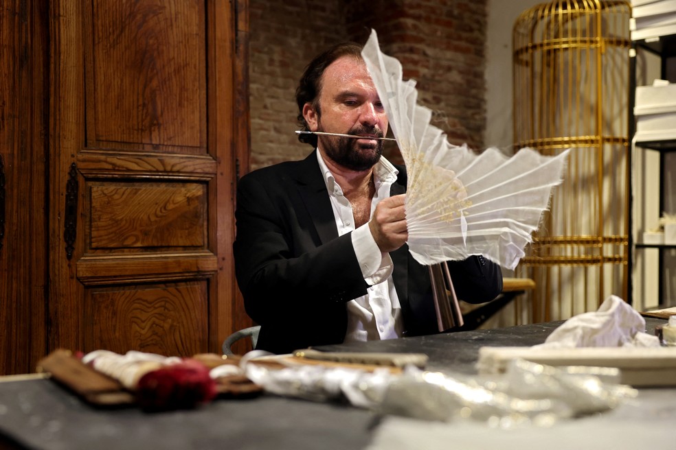 O designer francês de leques de luxo Olivier Bernoux trabalha em uma de suas criações em sua loja em Madri — Foto: Thomas Coex/AFP