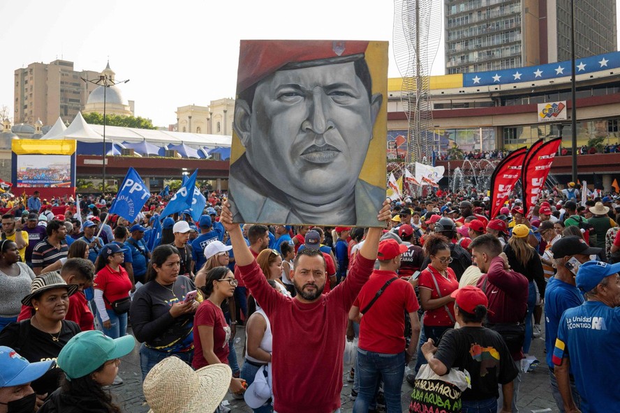 Apoiador do chavismo segurando cartaz do ex-presidente Hugo Chávez em comício
