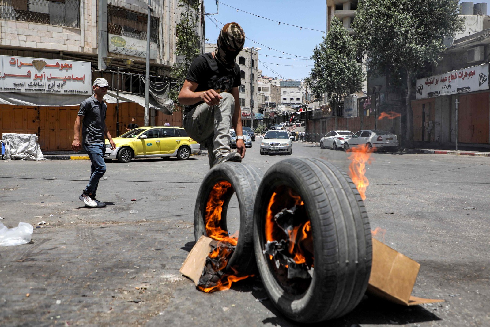 Manifestante palestino chuta um pneu em chamas durante confrontos com forças israelenses em Hebron, nesta terça-feira (4) — Foto: MOSAB SHAWER / AFP