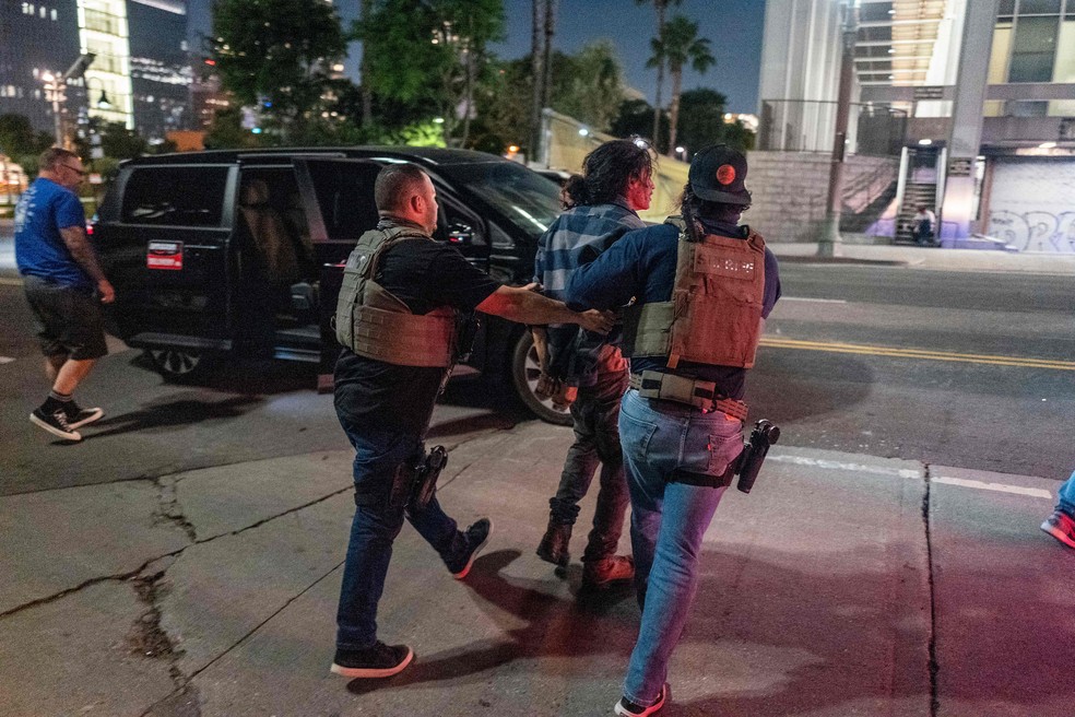 Policiais prendem um homem durante toque de recolher no centro de Los Angeles — Foto: RINGO CHIU / AFP