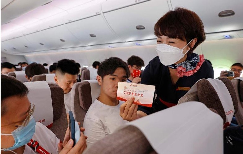 Passageiro tira fotos do cartão de embarque durante o primeiro voo comercial do jato de passageiros C919,  produzido na China  — Foto: AFP