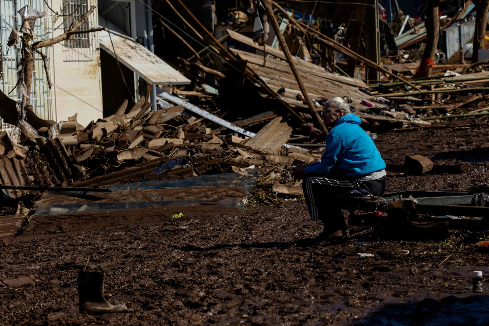 Uma mulher sentada em uma rua coberta de lama e detritos após um ciclone em Muçum, Rio Grande do Sul — Foto: SILVIO ÁVILA/AFP