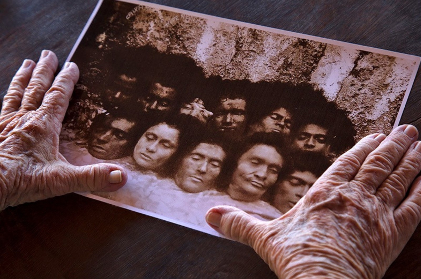 Mãos da testemunha Ana Agra sobre fotografia de cabeças cortadas no período do cangaço: imagem de Ricardo Beliel está no livro "Memórias sangradas: vida e morte nos tempos do cangaço"