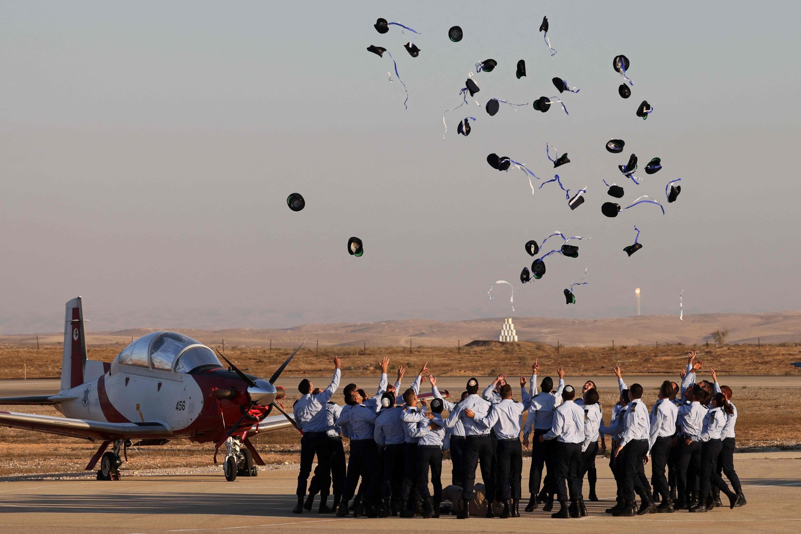 Pilotos da Força Aérea de Israel jogam seus chapéus para o ar durante a cerimônia de formatura na base de Hatzerim, no deserto de Negev, perto da cidade de Beer Sheva — Foto: MENAHEM KAHANA / AFP
