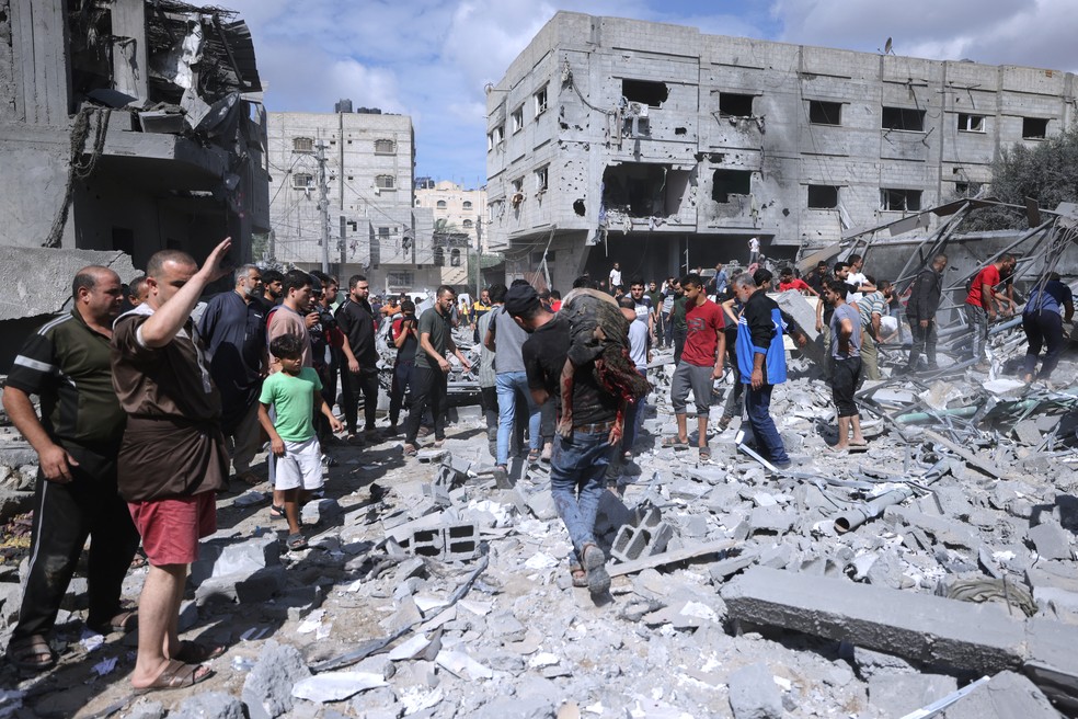 Palestinos se organizam para tentar retirar vtimas de escombro de prdio em Rafah.  Foto: Mohammed Abed/AFP