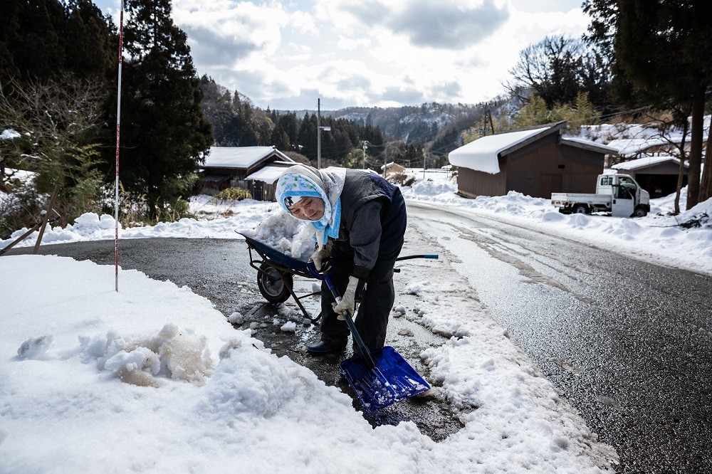 Mulher usa a pá para tirar a neve de frente da sua casa, na vila de Sasagawa, perto das antigas minas da Ilha Sado, no JapãoThe New York Times