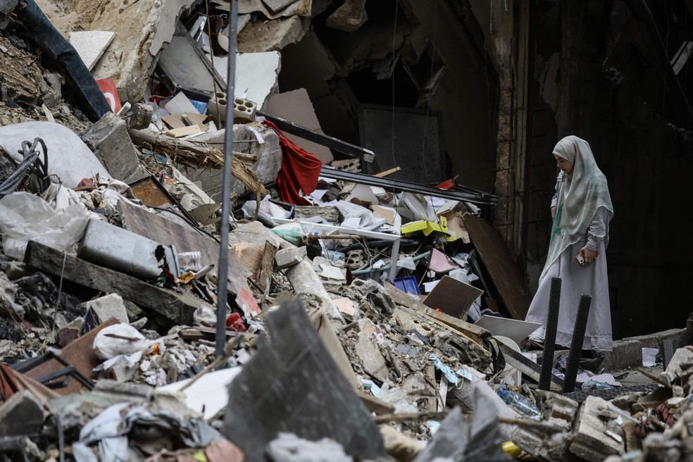 Uma mulher  em meio aos escombros de um prédio destruído na área de Haret Hreik, nos subúrbios do sul de Beirute — Foto: IBRAHIM AMRO/AFP