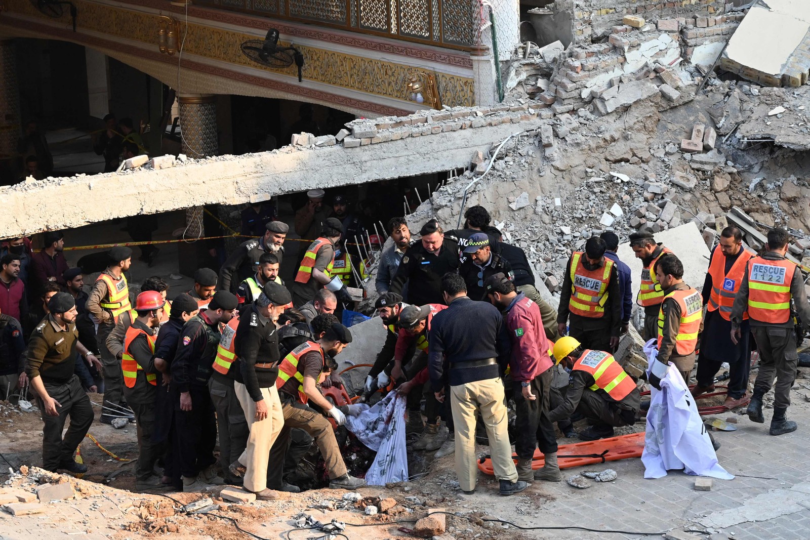 Equipes de resgate carregam os restos mortais de vítimas da explosão de uma mesquita no Paquistão — Foto: ABDUL MAJEED/AFP