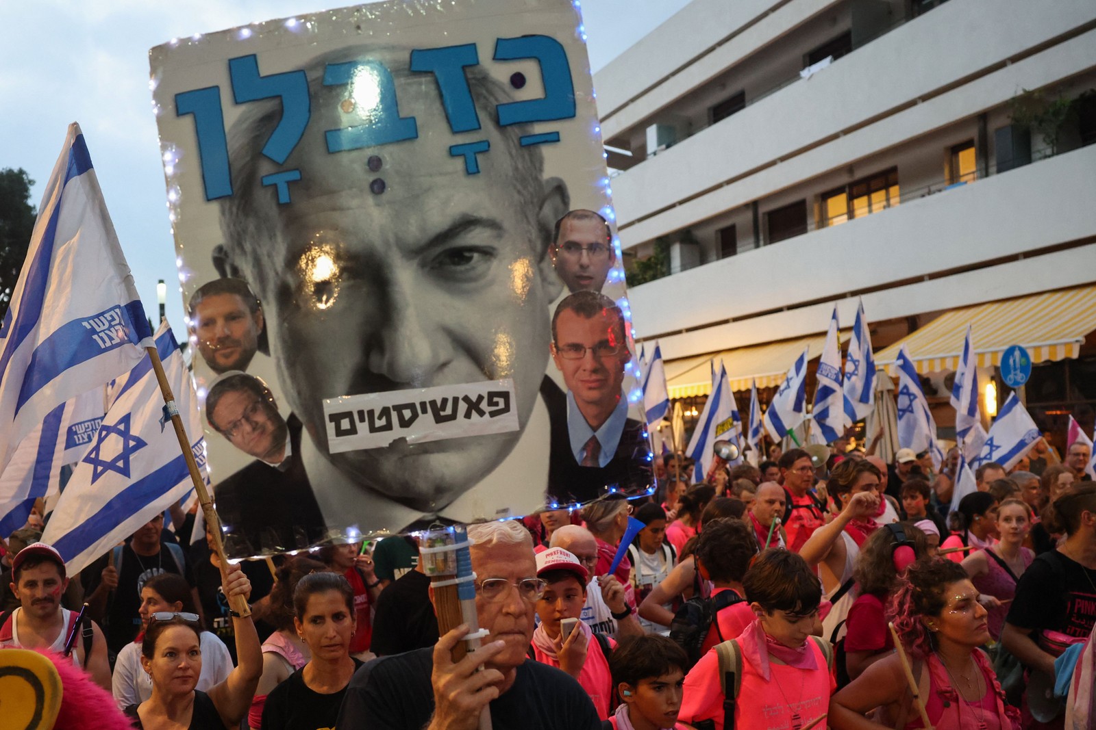 Manifestantes levantam bandeiras e cartazes durante uma manifestação contra o plano de revisão judicial do governo israelense em Tel Aviv — Foto: Jack Guez/AFP