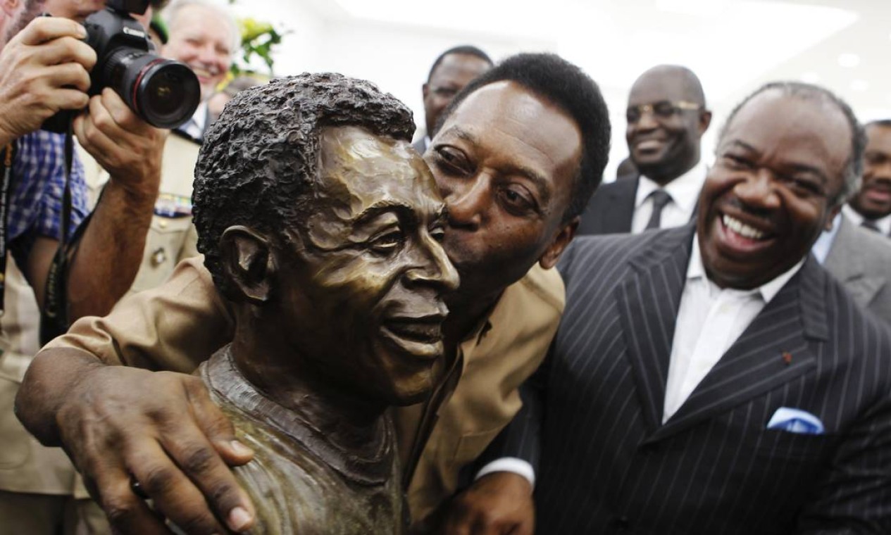 Pelé, em 2012, beija sua estátua enquanto o presidente do Gabão, Ali Bongo Ondimba, o assiste durante inauguração do monumento no Estádio De L'Amitie, em Libreville  — Foto: THOMAS MUKOYA / Reuters