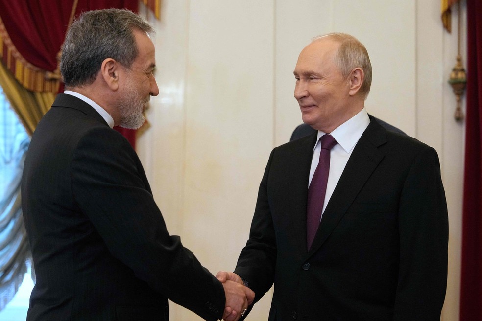 Putin e Araghchi se cumprimentam durante encontro em São Petersburgo nesta segunda-feira — Foto: Dmitry LOVETSKY/AFP