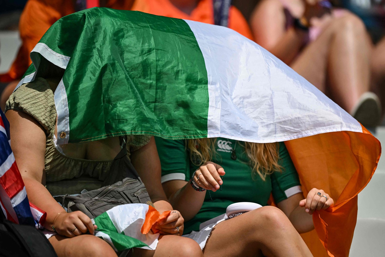 Supporters protect themselves from the heat during a women's rugby sevens match — Photo: Carl de Souza / AFP