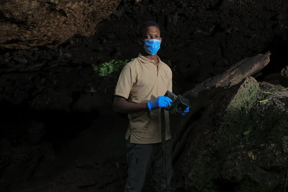 Bosco Atukwatse, biólogo da vida selvagem que trabalha no Projeto Leões de Kyambura, segura uma das câmeras de trilha com as quais trabalhou — Foto: Alexandre Braczkowski