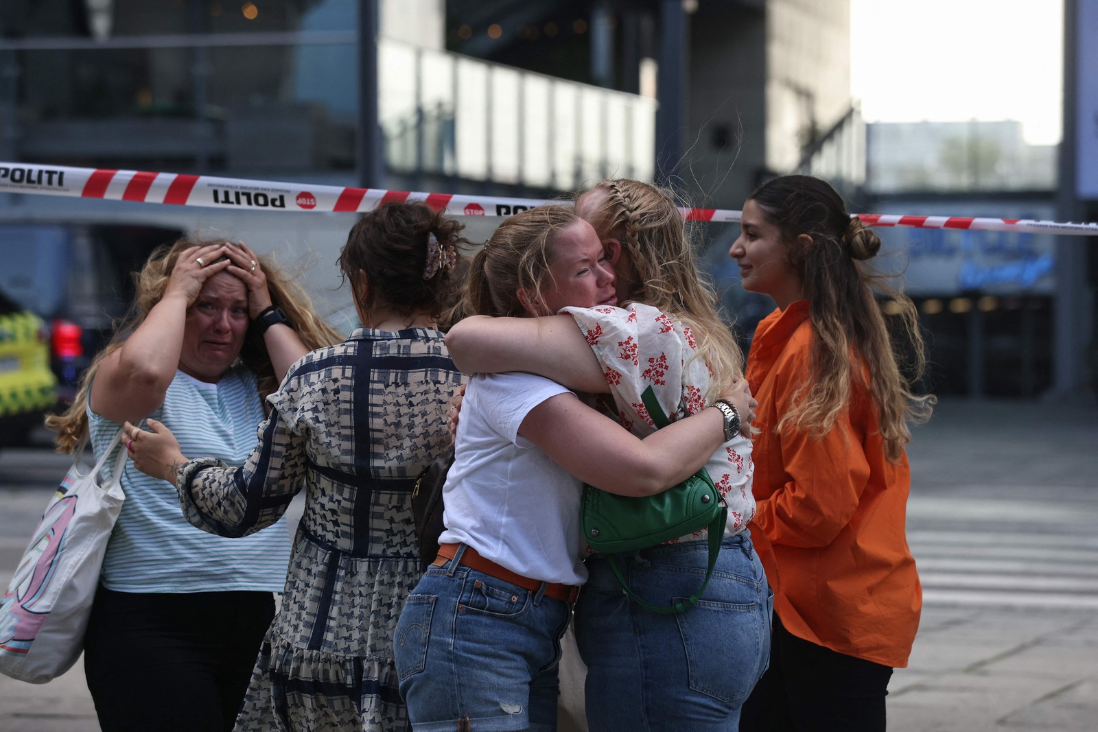 Pessoas conseguiram escapar do tiroteio no shopping se abraçam do lado de fora enquanto a polícia evacua a área  — Foto: Olafur Steinar Gestsson / Ritzau Scanpix / AFP